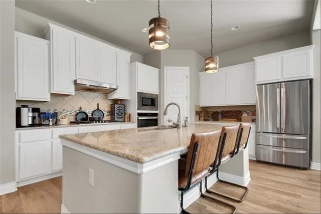 a kitchen with granite countertop a table chairs stove and refrigerator