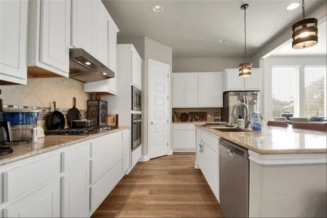 a kitchen with stainless steel appliances granite countertop a sink a stove and a refrigerator