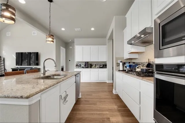 a large kitchen with stainless steel appliances granite countertop a sink and cabinets