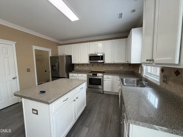 a kitchen with granite countertop a sink stove and refrigerator