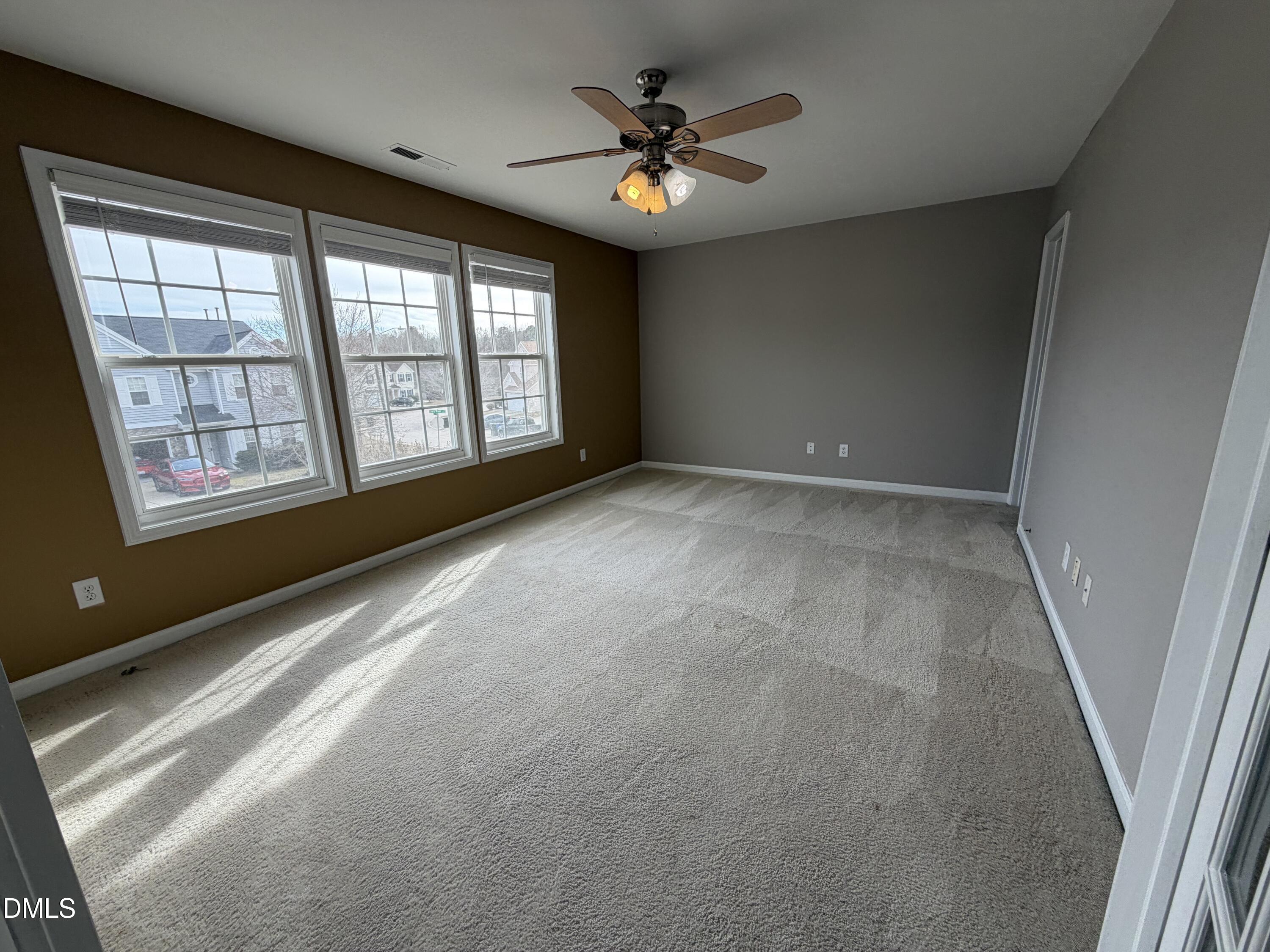 2418 Lazy River Drive Raleigh, NC 27610 - Photo 9 of 14 an empty room with chandelier fan and windows
