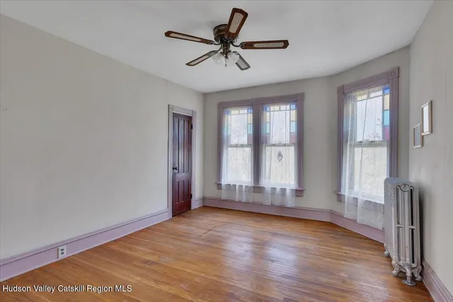 a view of a hallway with wooden floor and a bathroom