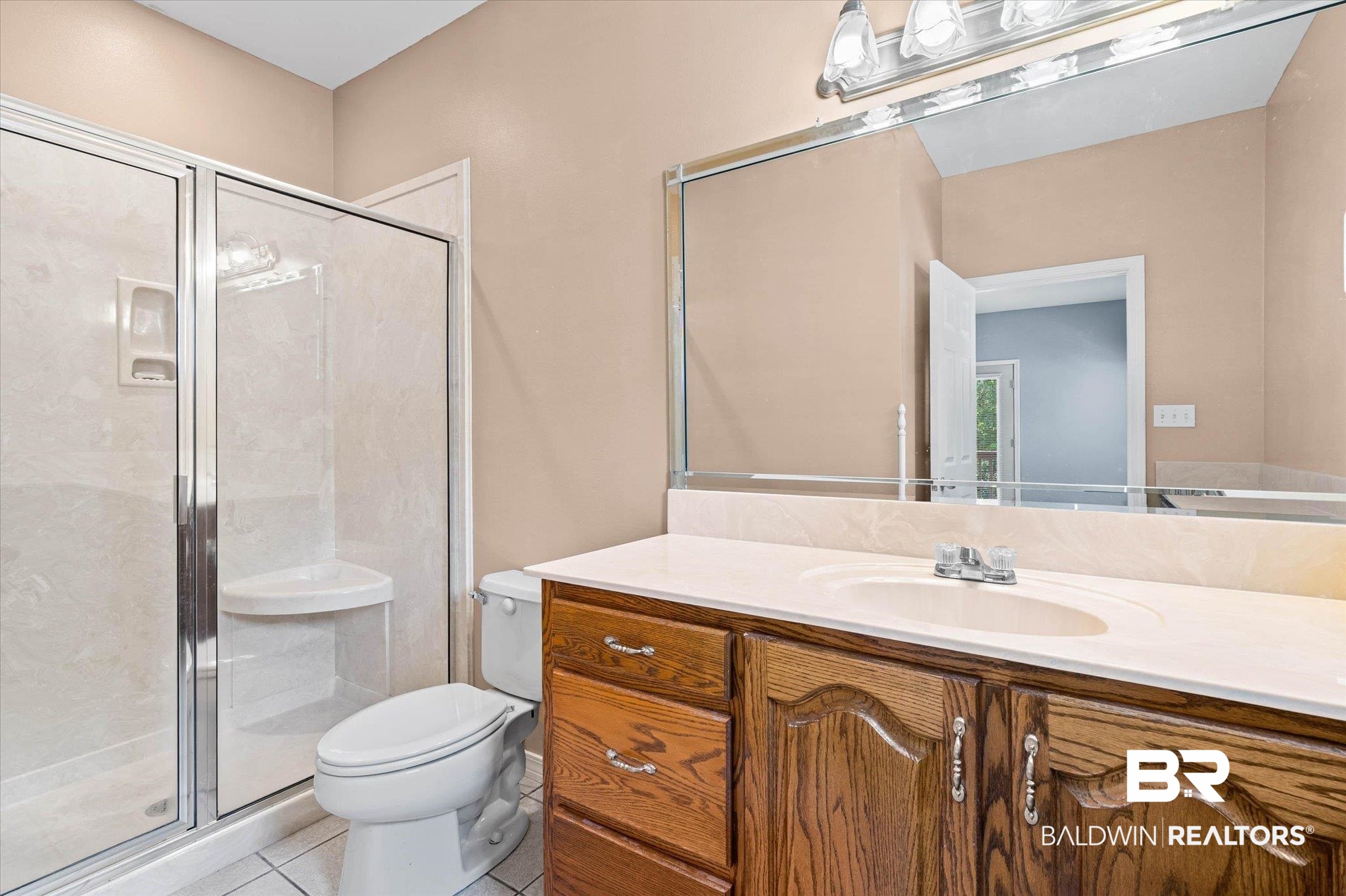 41923 Bayou Road Bay Minette, AL 36507 - Photo 16 of 35 Bathroom featuring a glass-enclosed shower, a corner shower seat, a vanity with wood-finish cabinetry, a single basin sink, and a large wall-mounted mirror