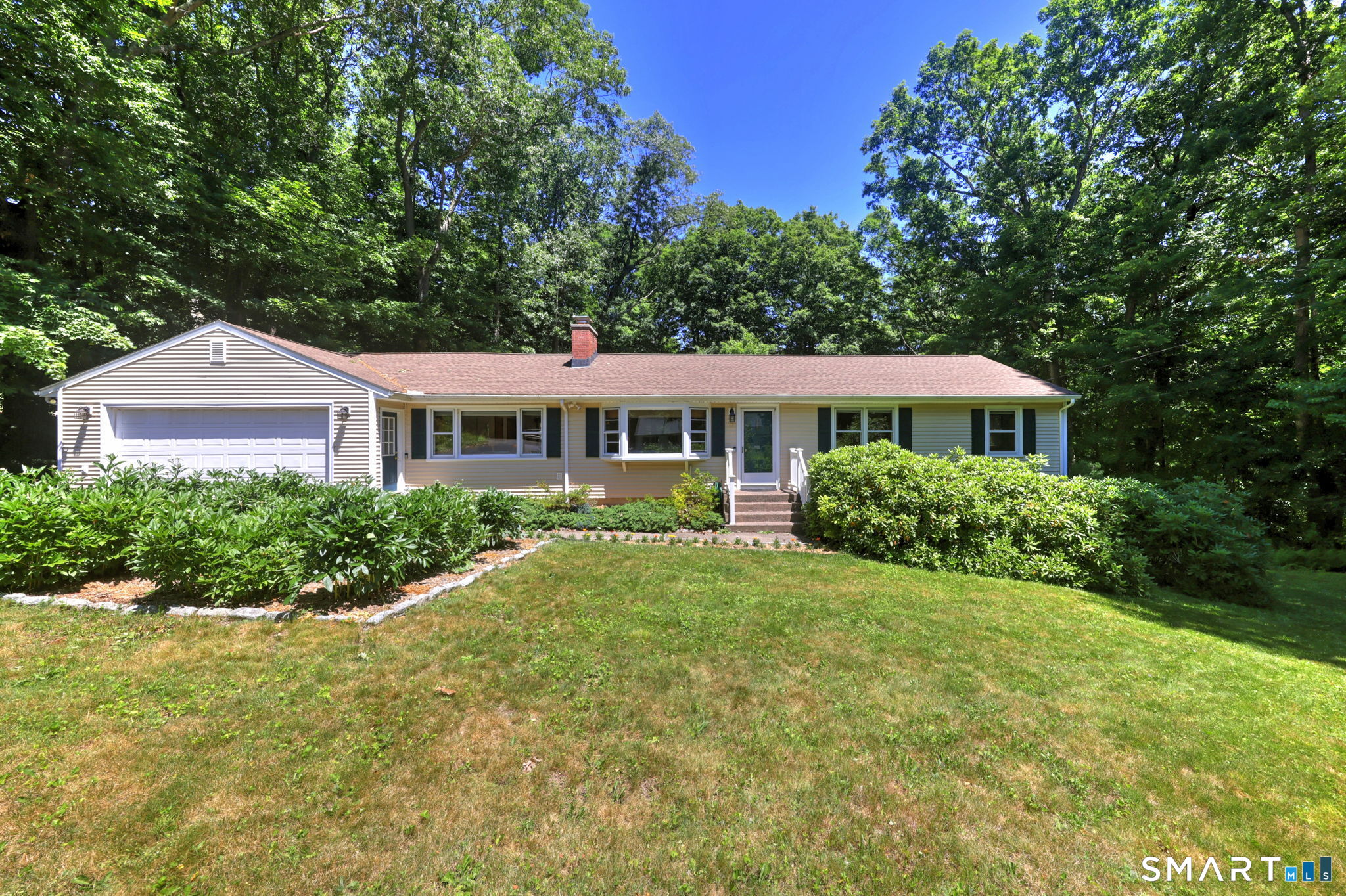 Beautiful gently sloping front yard with established mature shrubs.