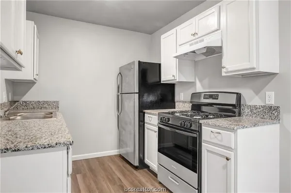 a kitchen with granite countertop cabinets stainless steel appliances and wooden floor