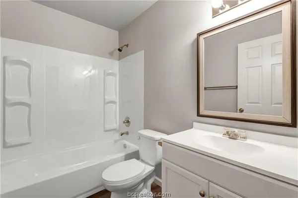 a bathroom with a granite countertop sink toilet a mirror and shower