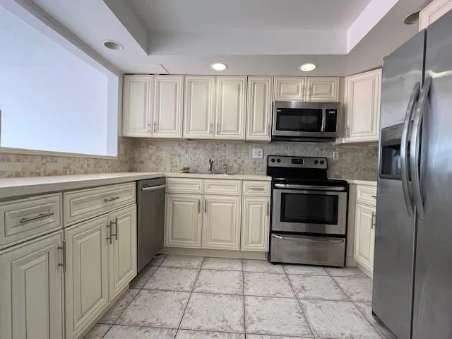 a kitchen with cabinets stainless steel appliances and a window