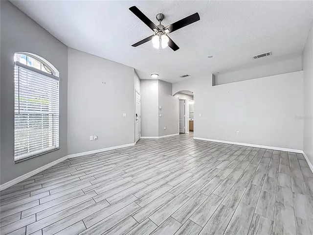 an empty room with wooden floor and windows