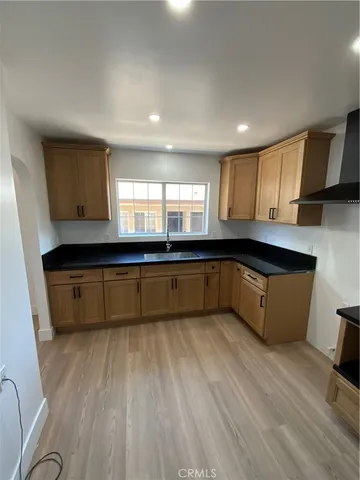 a large kitchen with a large counter top space a sink a window and stainless steel appliances