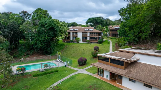 an aerial view of a house with lots of residential buildings ocean and mountain view in back