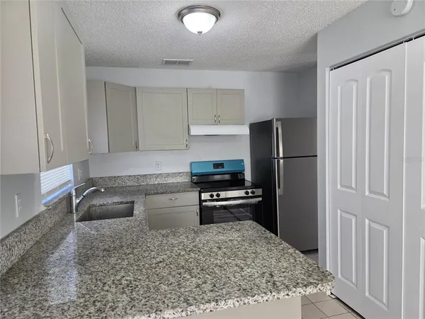 a kitchen with granite countertop a refrigerator and a sink