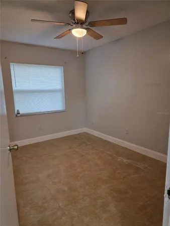 an empty room with a window and a fan