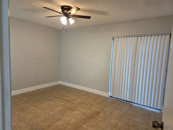 an empty room with a ceiling fan and a window