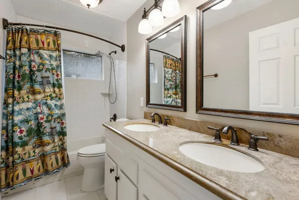 a bathroom with a granite countertop sink mirror vanity and toilet