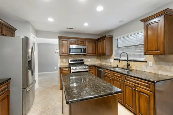a kitchen with stainless steel appliances granite countertop a sink stove microwave and refrigerator