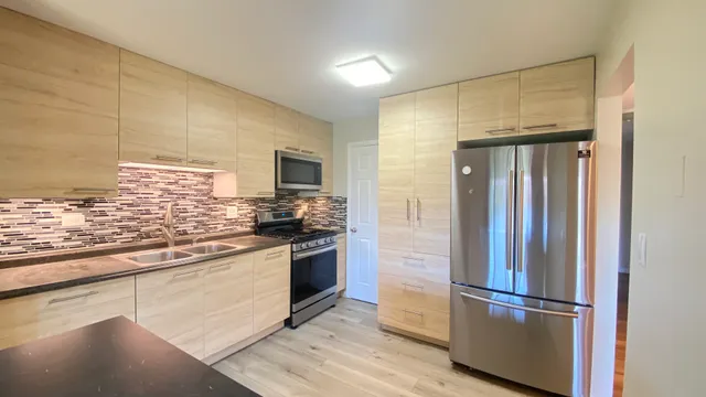 a kitchen with stainless steel appliances granite countertop a refrigerator and a stove top oven
