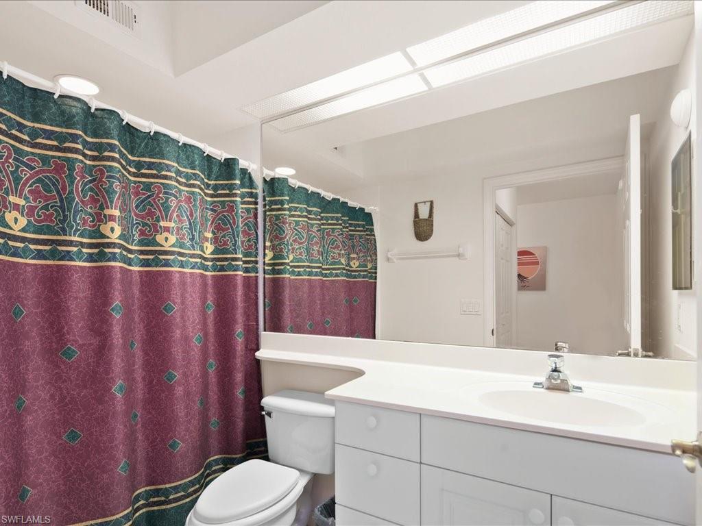 10910 Oak Island Road, Unit 103 Estero, FL 34135 - Photo 15 of 24 a bathroom with a sink a toilet a mirror and shower curtain