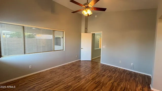 a view of an empty room with a window and a kitchen