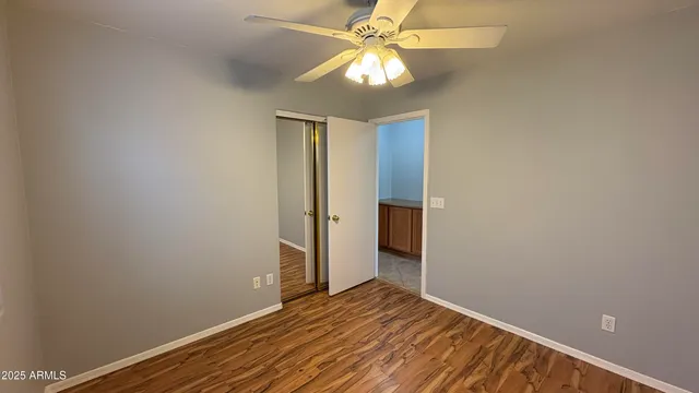 an empty room with wooden floor fan and windows