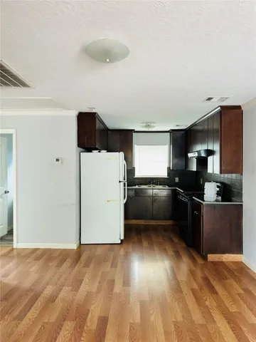 a kitchen with granite countertop a refrigerator and a stove top oven