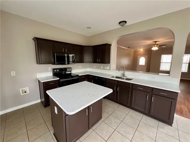 a kitchen with kitchen island granite countertop a stove microwave and sink
