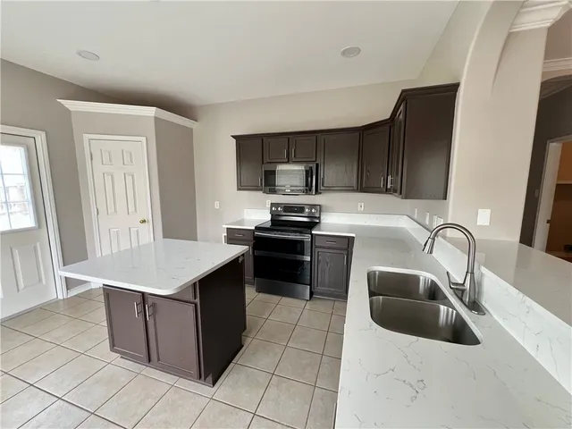 a kitchen with stainless steel appliances granite countertop a sink a stove a microwave a counter top and cabinets