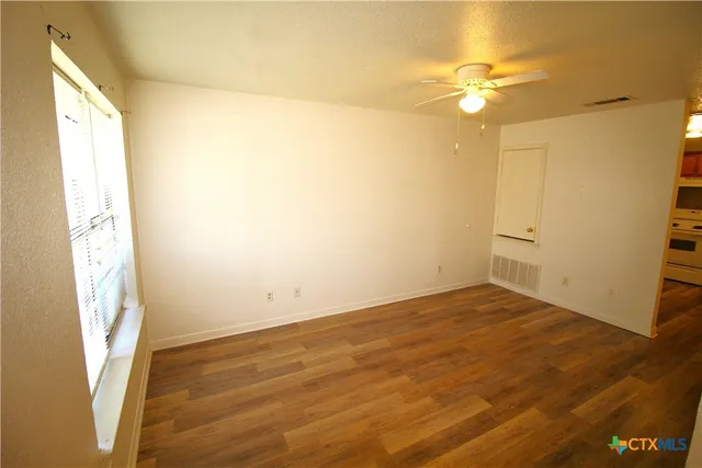 a view of an empty room with wooden floor and a window