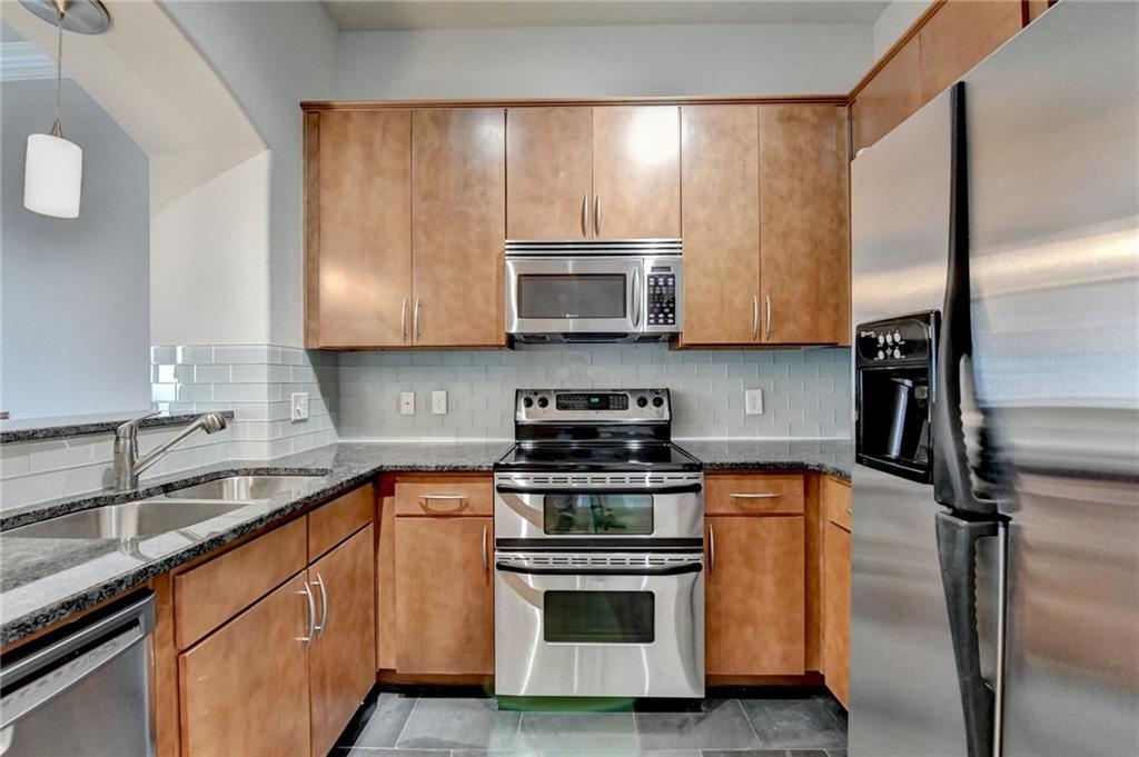 3445 Stratford Road Northeast, Unit 2106 Atlanta, GA 30326 - Photo 6 of 44 a kitchen with stainless steel appliances wooden cabinets sink and a granite counter top
