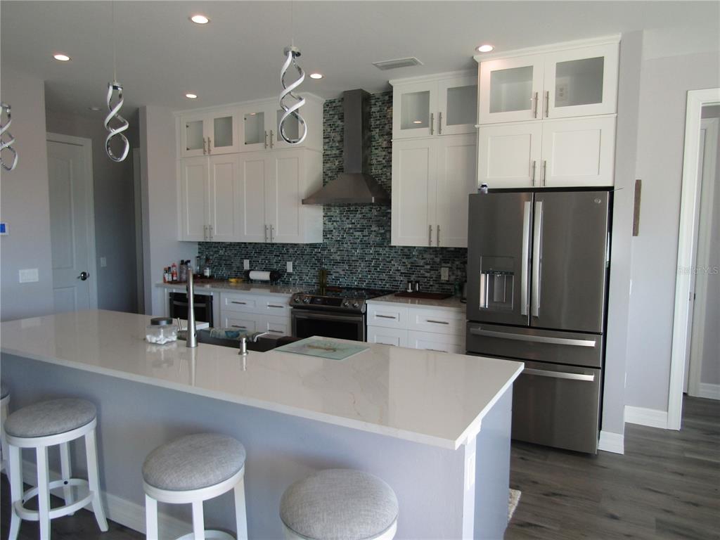 a kitchen with stainless steel appliances a refrigerator a sink a stove a dining table and chairs