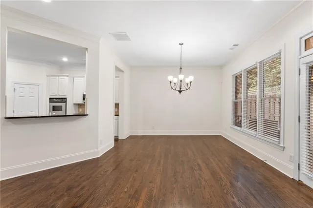 a view of empty room with wooden floor and kitchen view
