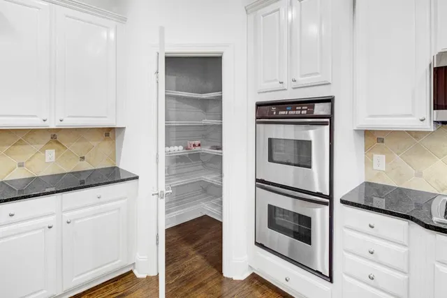 a kitchen with granite countertop white cabinets and stainless steel appliances