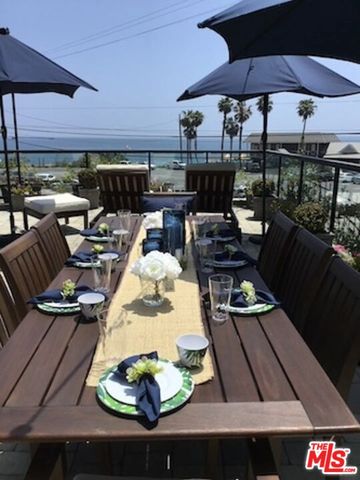 a view of a patio with couches table and chairs under an umbrella with a barbeque