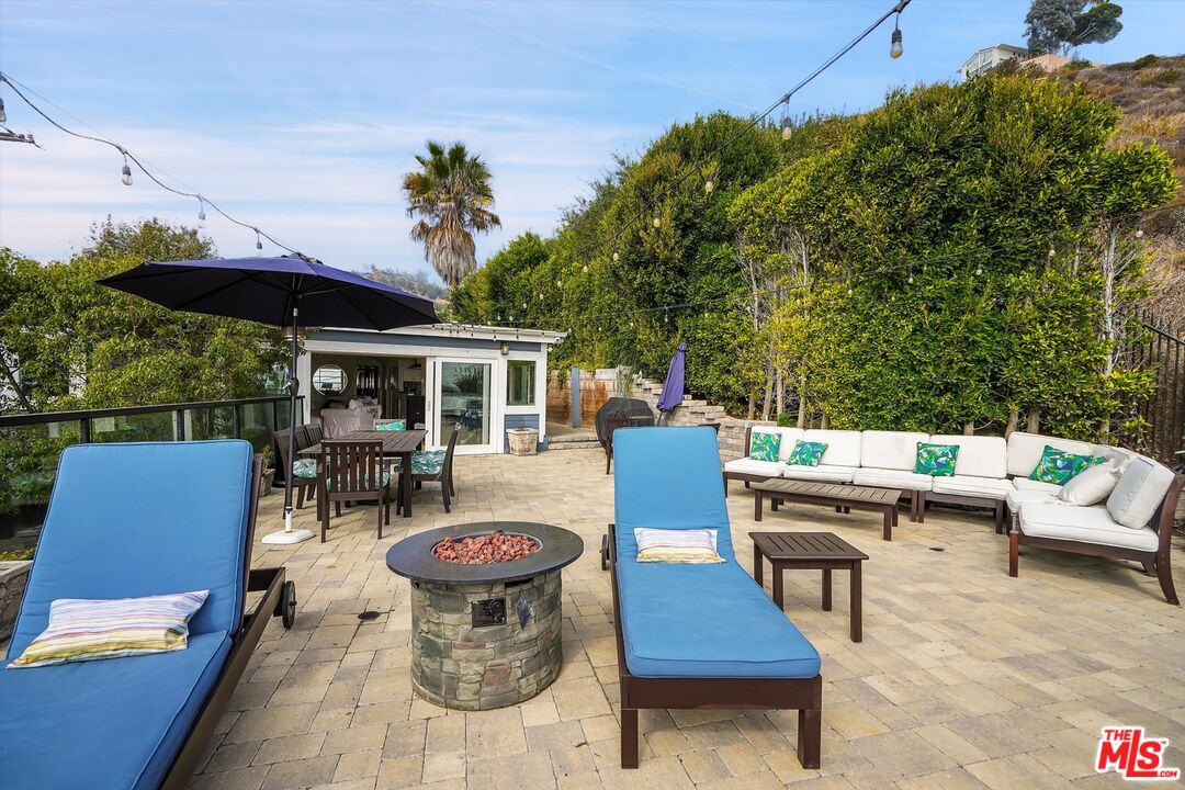 3966 Las Flores Canyon Road Malibu, CA 90265 - Photo 16 of 53 a view of a patio with a dining table and chairs with a fire pit