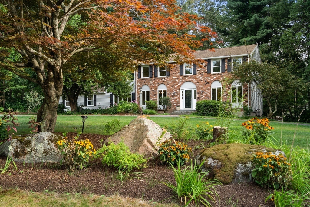 a front view of a house with a garden and trees