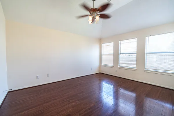 an empty room with wooden floor and windows