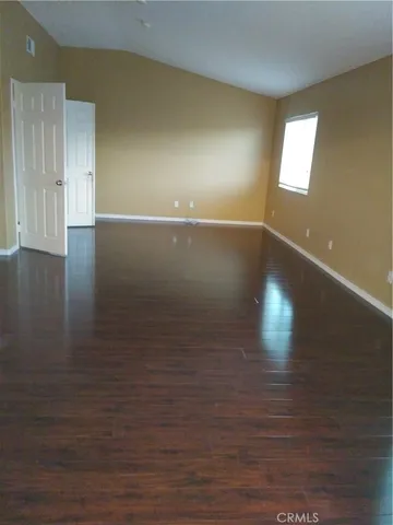 an empty room with wooden floor and windows in it