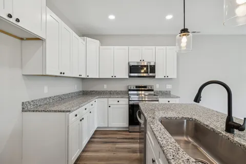 a kitchen with kitchen island granite countertop a sink a counter space appliances and cabinets