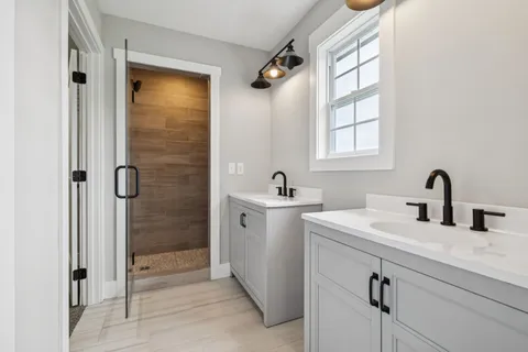 a bathroom with a double vanity sink a mirror and shower