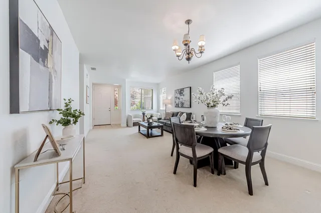 a kitchen with stainless steel appliances granite countertop a stove top oven a refrigerator a sink with a dining table and chairs with wooden floor