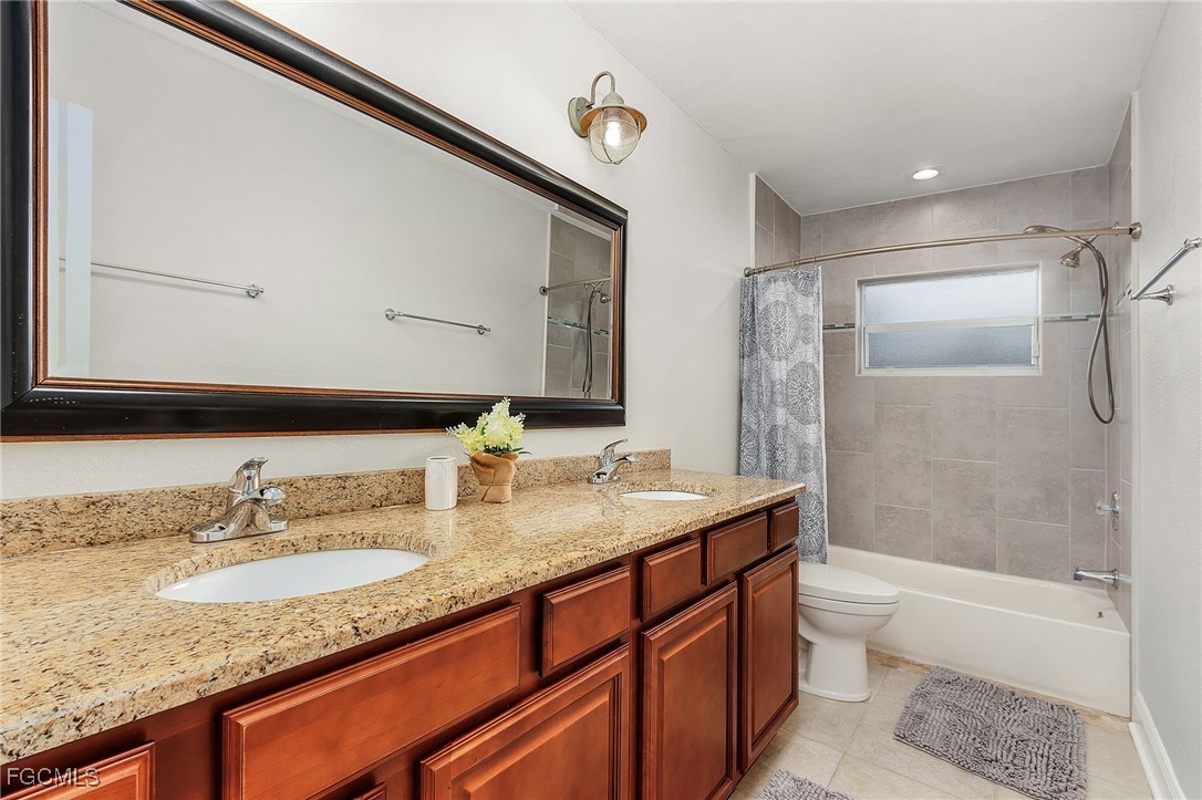 5730 Winkler Road Fort Myers, FL 33919 - Photo 19 of 37 a bathroom with a granite countertop sink mirror toilet and bathtub