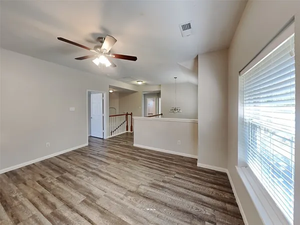 a view of an empty room with window and wooden floor