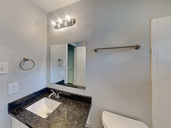 a bathroom with a granite countertop sink a toilet and mirror