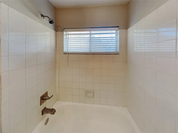 a bathroom with a window a toilet and a bathtub