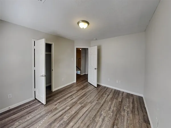 a view of an empty room with wooden floor and closet
