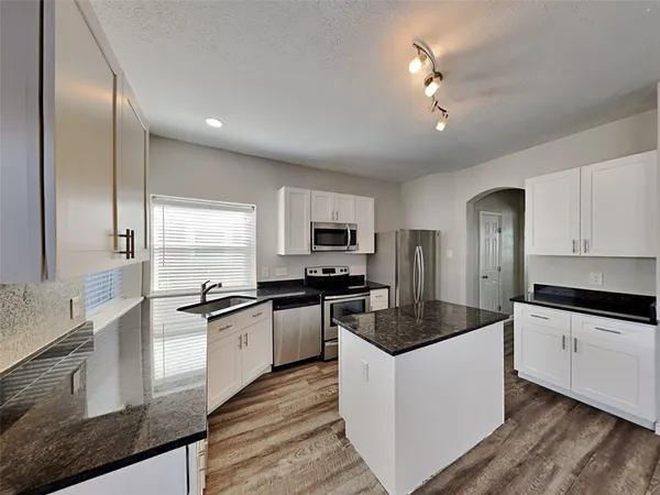 a kitchen with stainless steel appliances granite countertop a sink a stove and refrigerator