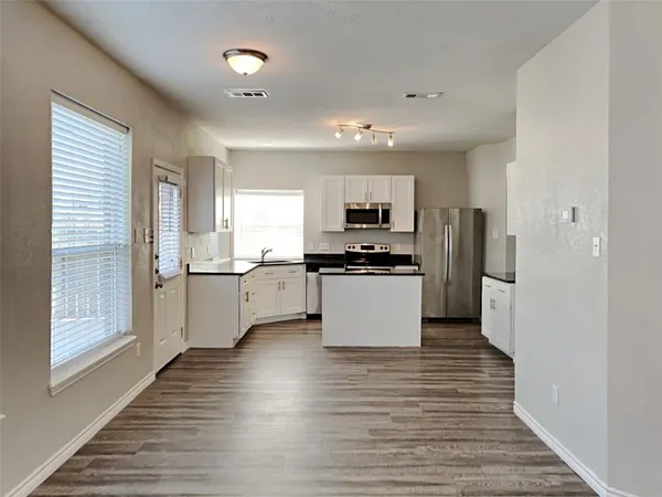 a kitchen with a refrigerator and white cabinets