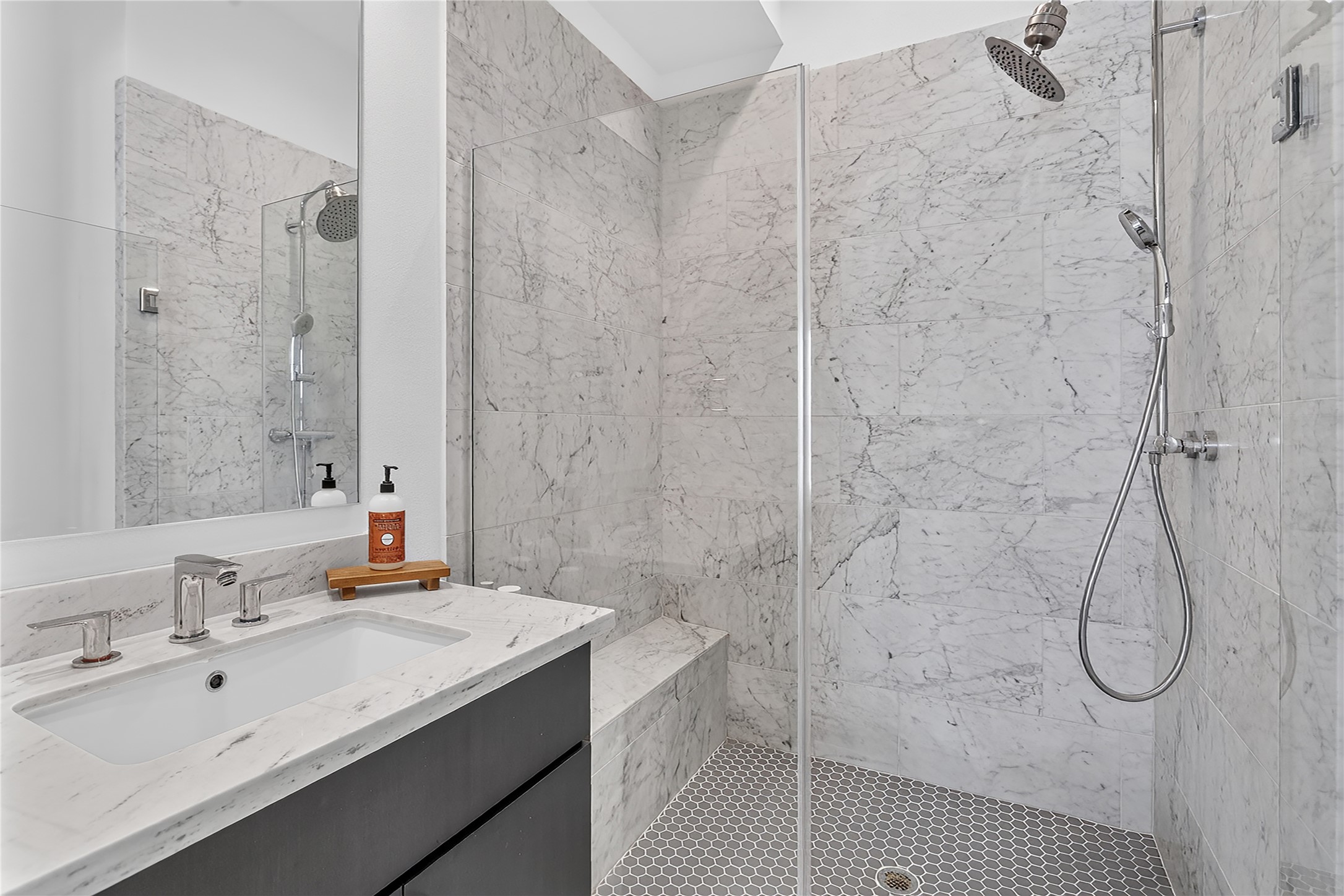 2805 McCurdy Street, Unit 14 Austin, TX 78723 - Photo 24 of 40 Marble-clad shower features a rainfall head, handheld sprayer, and built-in bench.