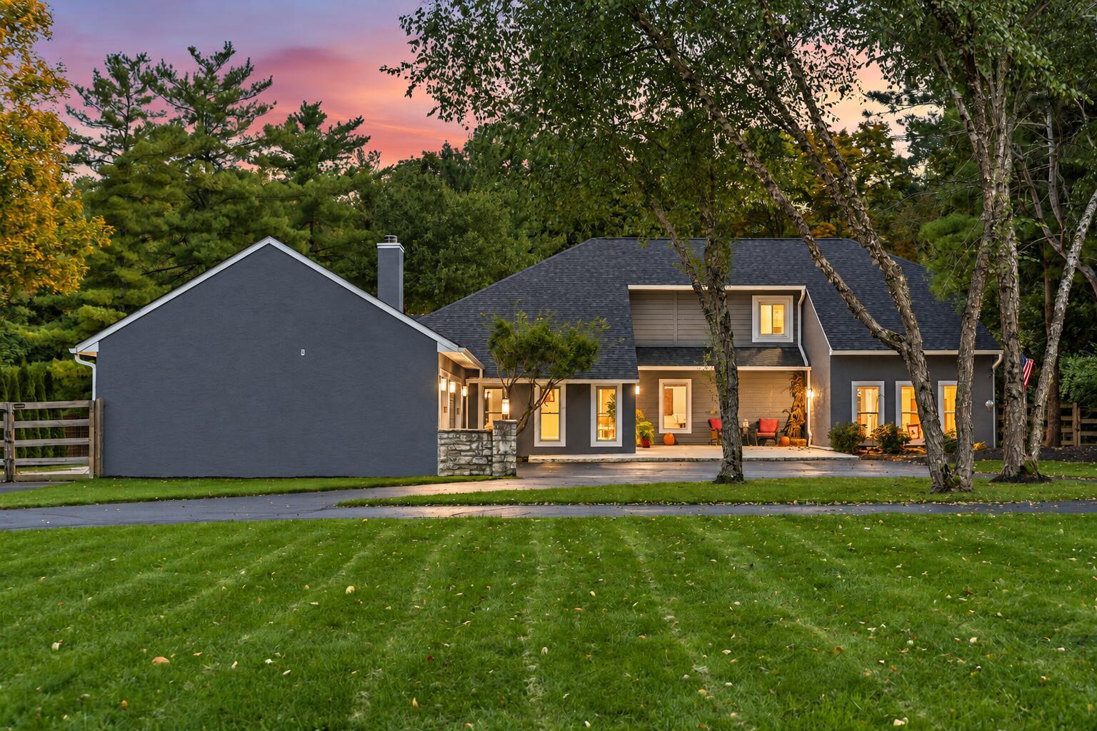 7140 Cook Road Powell, OH 43065 - Photo 7 of 87 Expansive front lawn with mature trees, a paved driveway, and a stone accent wall