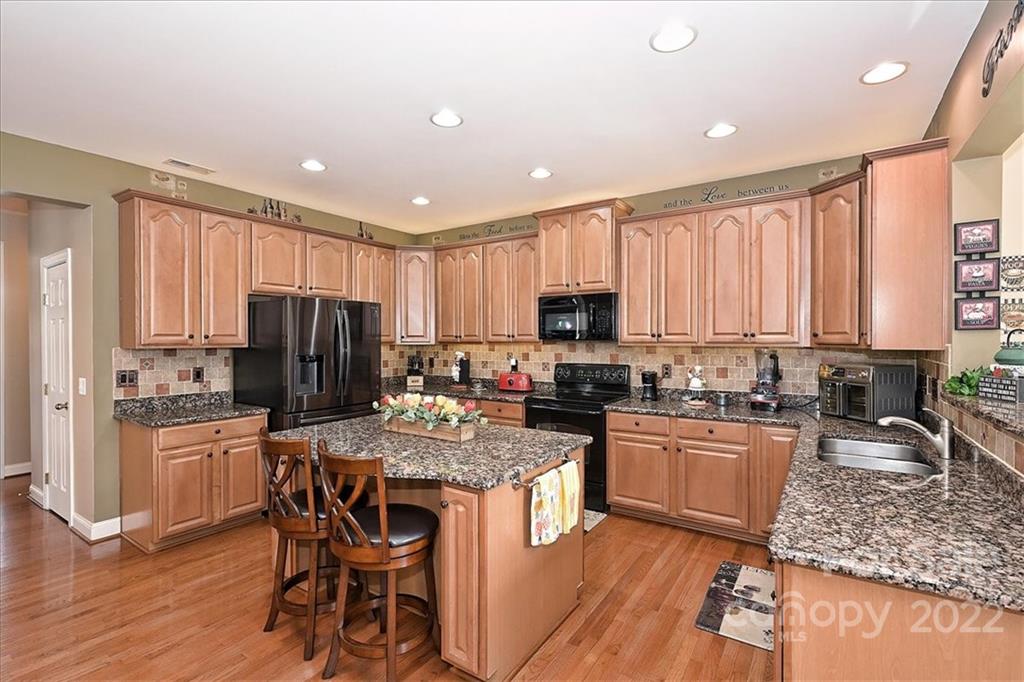 728 Beille Lane Fort Mill, SC 29708 - Photo 19 of 48 a kitchen with stainless steel appliances granite countertop a stove top oven a refrigerator a sink and dishwasher with wooden floor