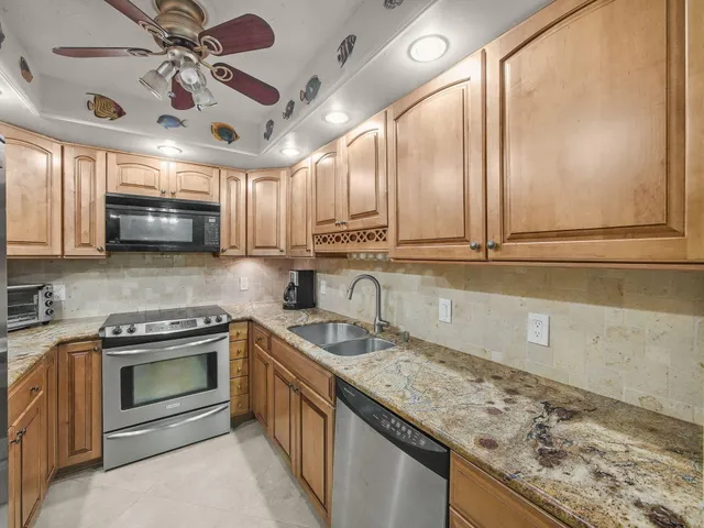 a kitchen with stainless steel appliances granite countertop a sink a stove and cabinets
